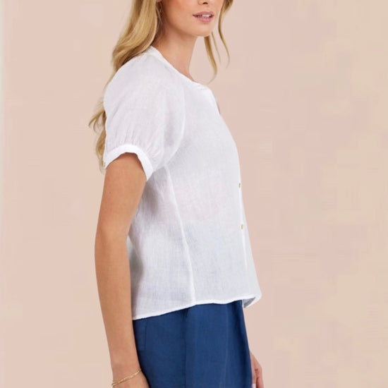 Woman wearing a white blouse and blue shorts on a beige background