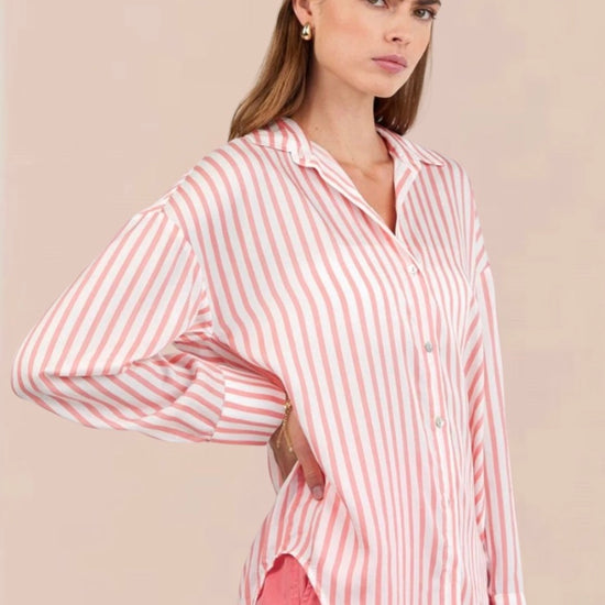Woman wearing a pink and white striped shirt and shorts on a beige background