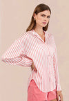 Woman wearing a pink and white striped shirt and shorts on a beige background