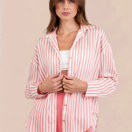 Woman wearing a pink and white striped shirt and shorts on a beige background