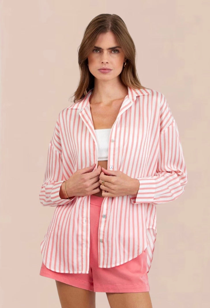 Woman wearing a pink and white striped shirt and shorts on a beige background