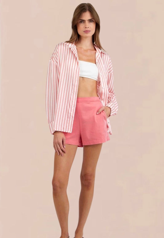 Woman wearing a pink and white striped shirt and shorts on a beige background
