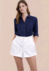 Woman wearing a navy blue shirt and white shorts on a beige background