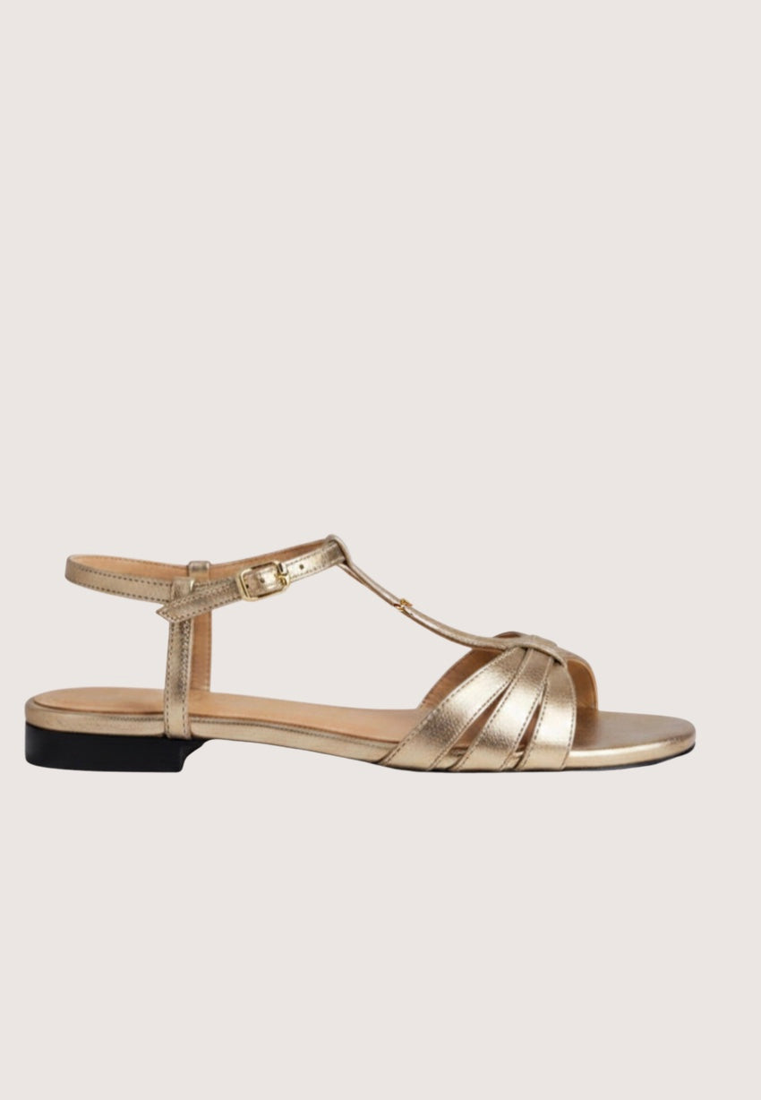 Gold sandal with a black sole on a light gray background