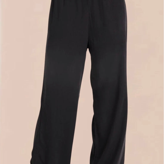 A pair of vintage black smocked waist trousers with wide-leg shape, side pockets, and an elasticated waistband.