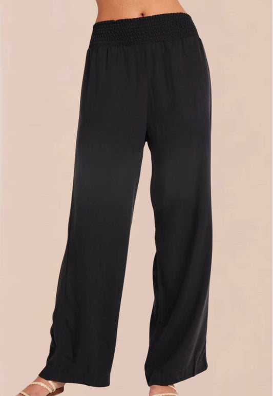 A pair of vintage black smocked waist trousers with wide-leg shape, side pockets, and an elasticated waistband.