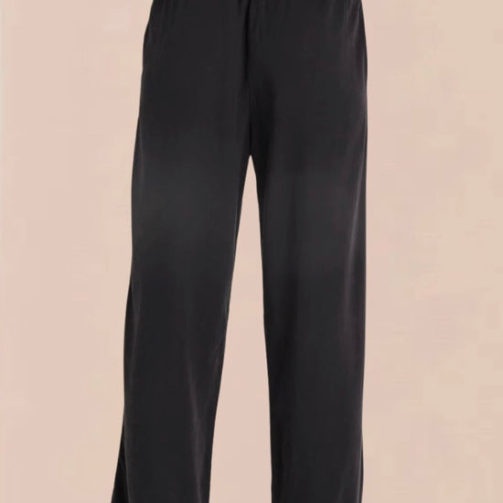 A pair of vintage black smocked waist trousers with wide-leg shape, side pockets, and an elasticated waistband.