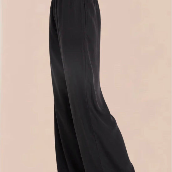 A pair of vintage black smocked waist trousers with wide-leg shape, side pockets, and an elasticated waistband.