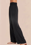 A pair of vintage black smocked waist trousers with wide-leg shape, side pockets, and an elasticated waistband.