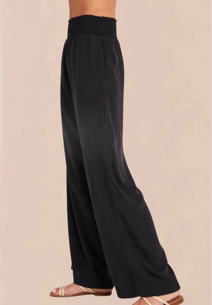 A pair of vintage black smocked waist trousers with wide-leg shape, side pockets, and an elasticated waistband.