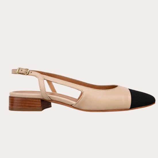 Sandal with beige upper and black cap toe on a light gray background