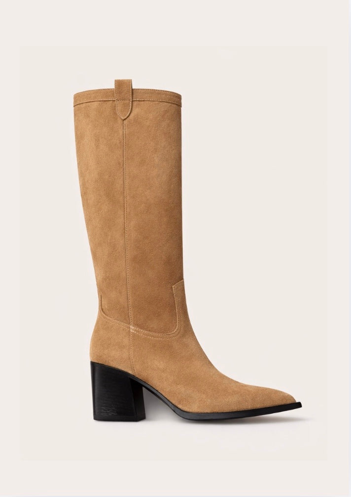 Tan knee-high  cow boy boot with a black block heel on a light beige background