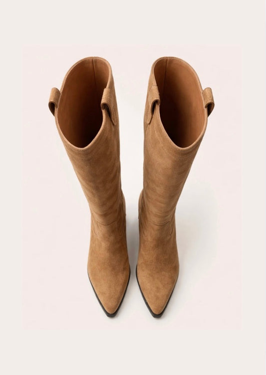 Tan knee-high  cow boy boot with a black block heel on a light beige background