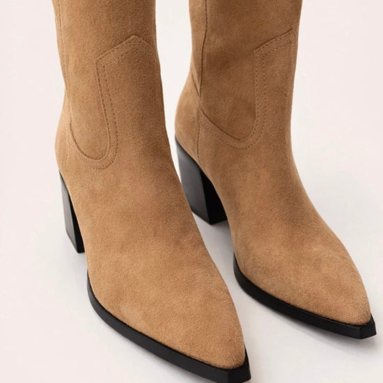 Tan knee-high  cow boy boot with a black block heel on a light beige background