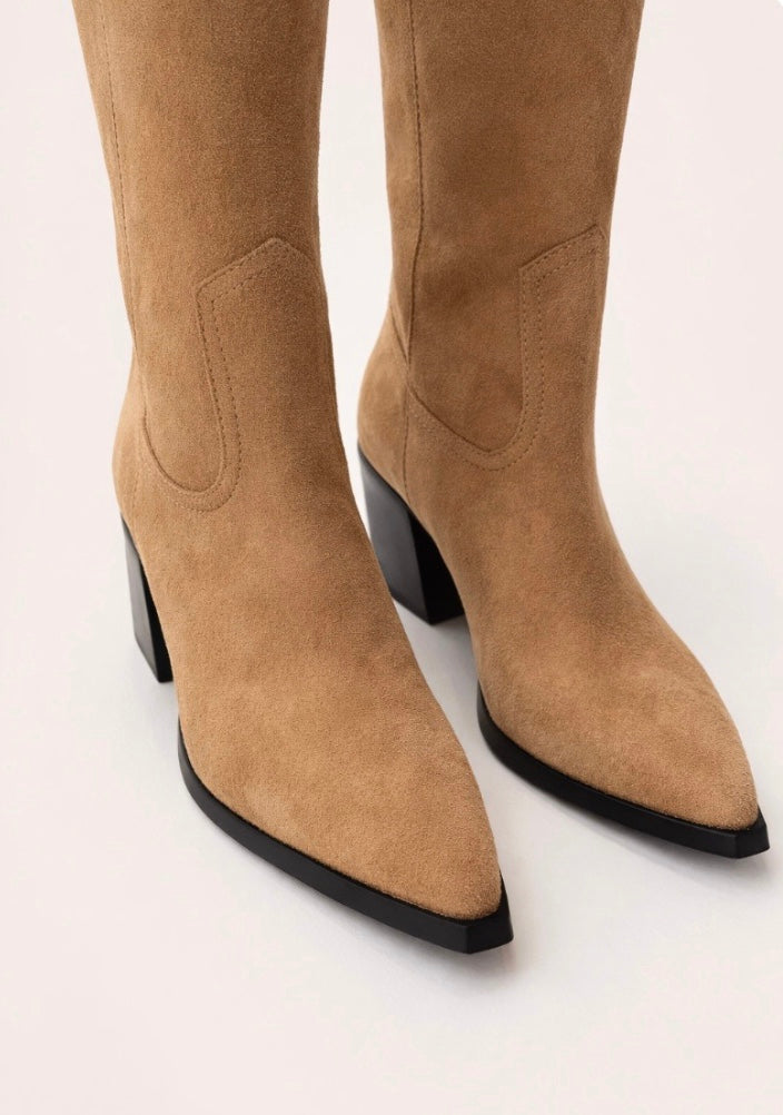 Tan knee-high  cow boy boot with a black block heel on a light beige background