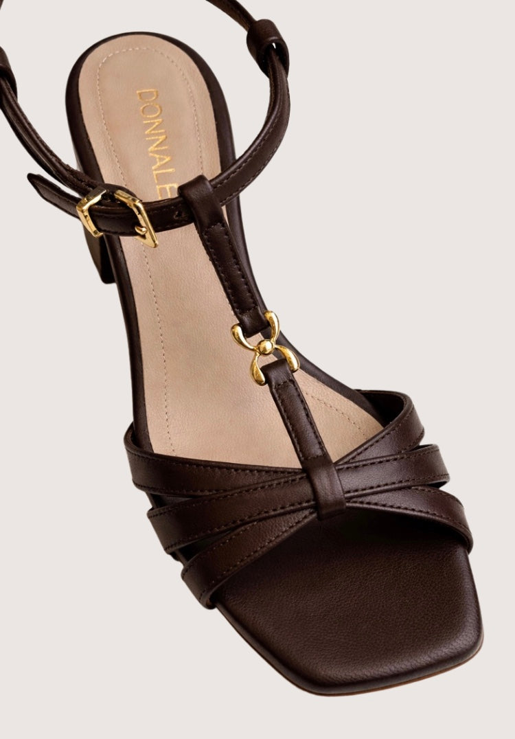 Brown sandal with gold accents on a light gray background