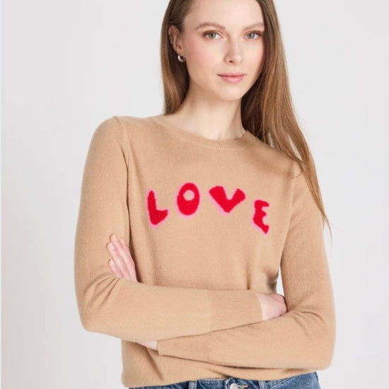 Woman wearing a beige sweater with 'LOVE' printed in red on a white background