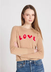 Woman wearing a beige sweater with 'LOVE' printed in red on a white background