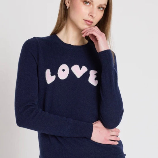 Woman wearing a navy sweater with 'LOVE' printed on it against a white background