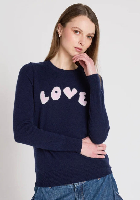 Woman wearing a navy sweater with 'LOVE' printed on it against a white background