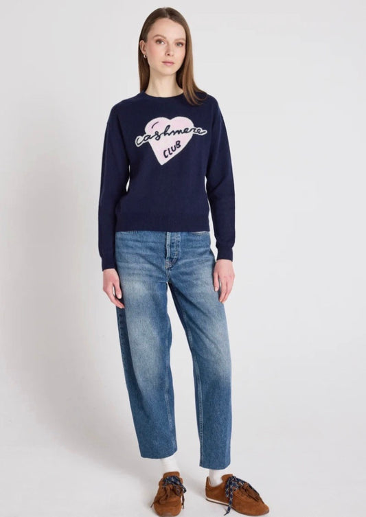 Model wearing a navy jumper and blue jeans on a white backgrounds