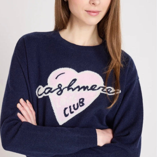 Close up model shot wearing a navy jumper with slogan on it on a white background 