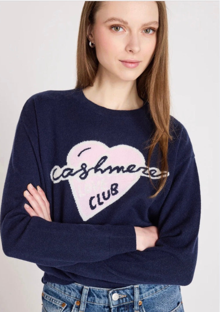 Close up model shot wearing a navy jumper with slogan on it on a white background 