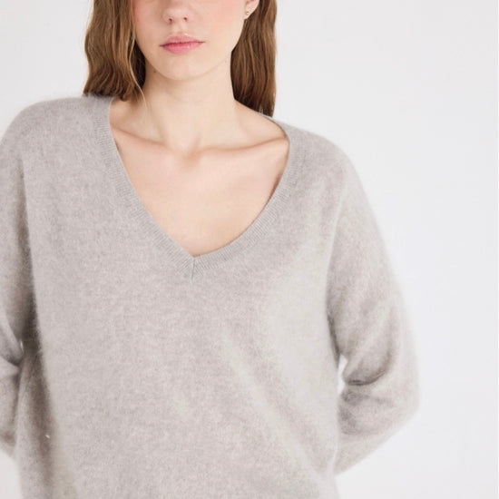 Woman wearing a light gray sweater against a white background