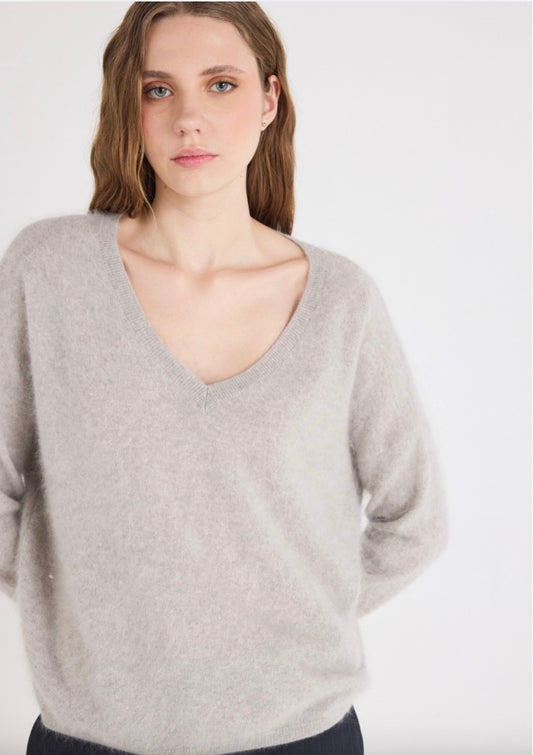 Woman wearing a light gray sweater against a white background