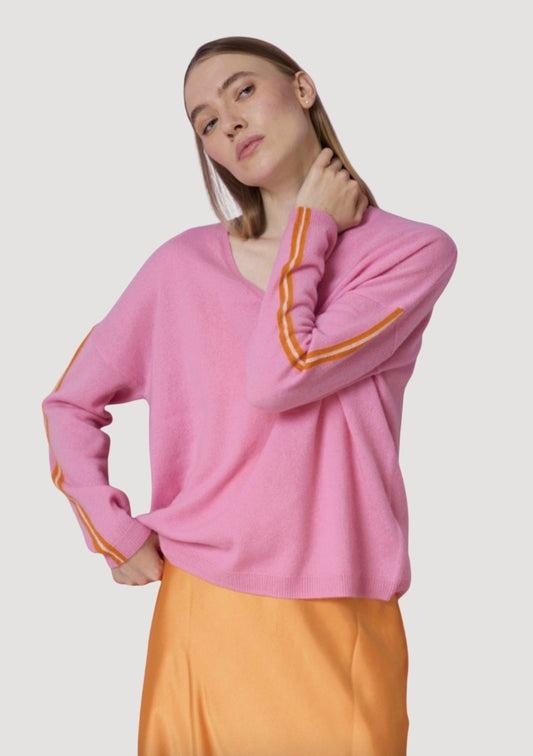 Person wearing a pink sweater with orange accents on a plain background
