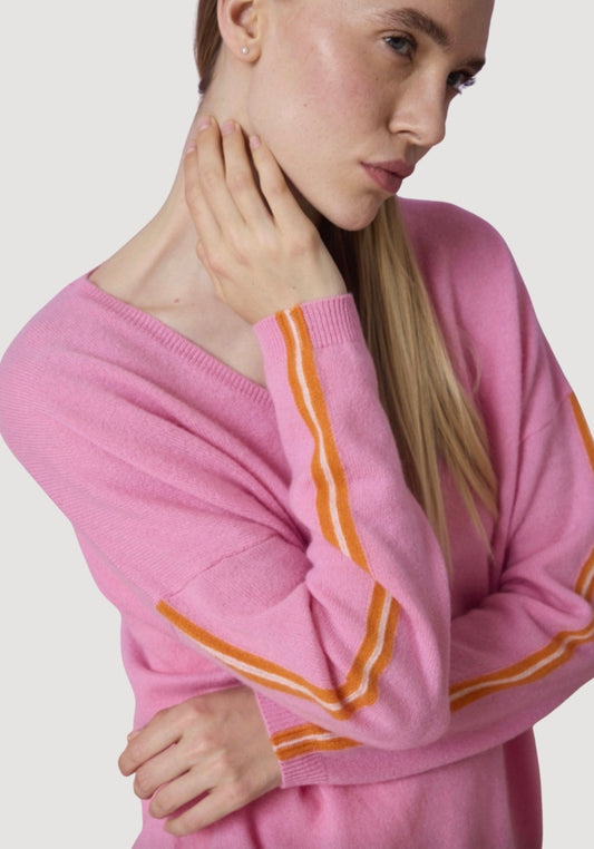 Person wearing a pink sweater with orange stripes on a plain background