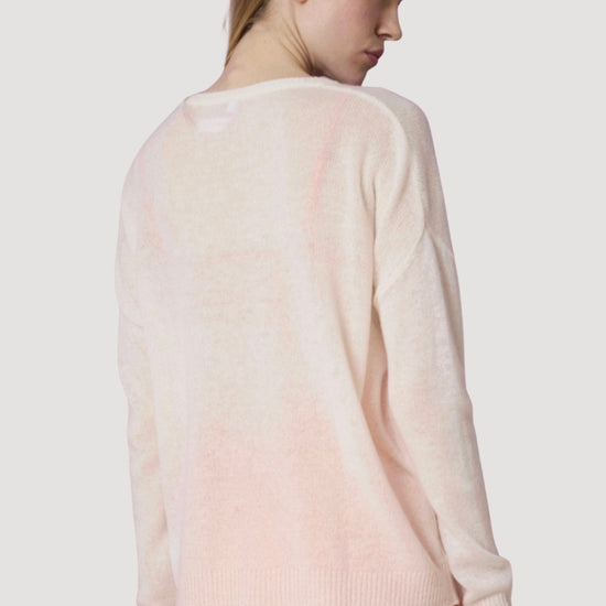 Woman wearing a light pink sweater and orange pants on a white background
