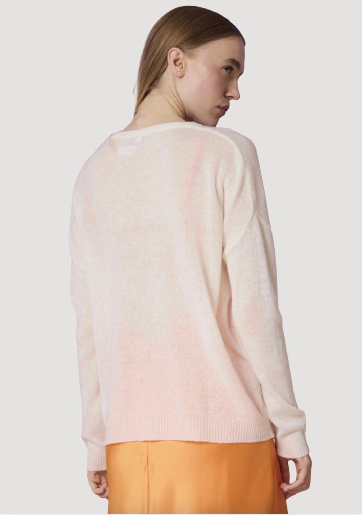 Woman wearing a light pink sweater and orange pants on a white background