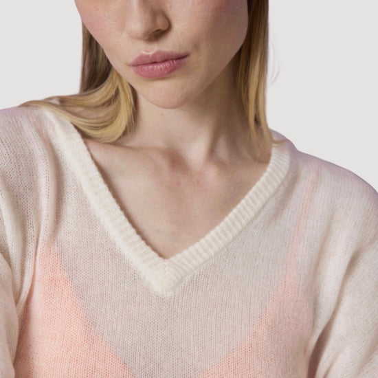 Woman wearing a light pink sweater with a neutral background