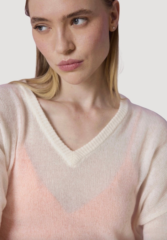 Woman wearing a light pink sweater with a neutral background
