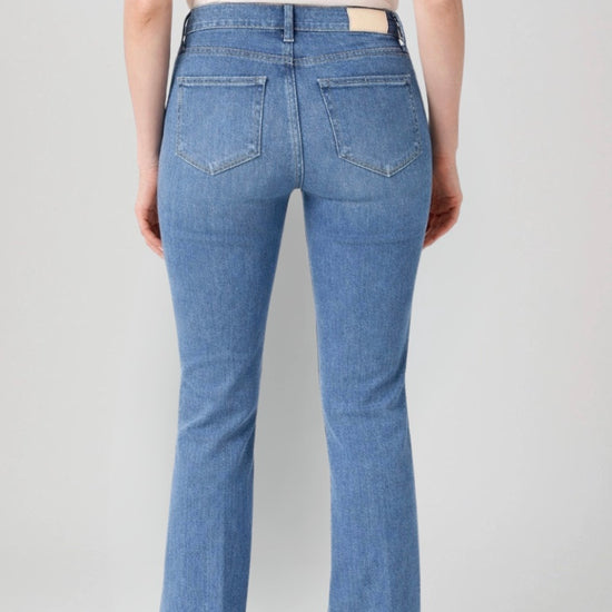 Blue jeans worn by a person on a plain background