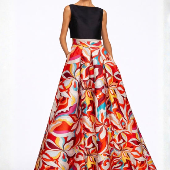 Woman wearing a black top and colorful patterned skirt on a white background