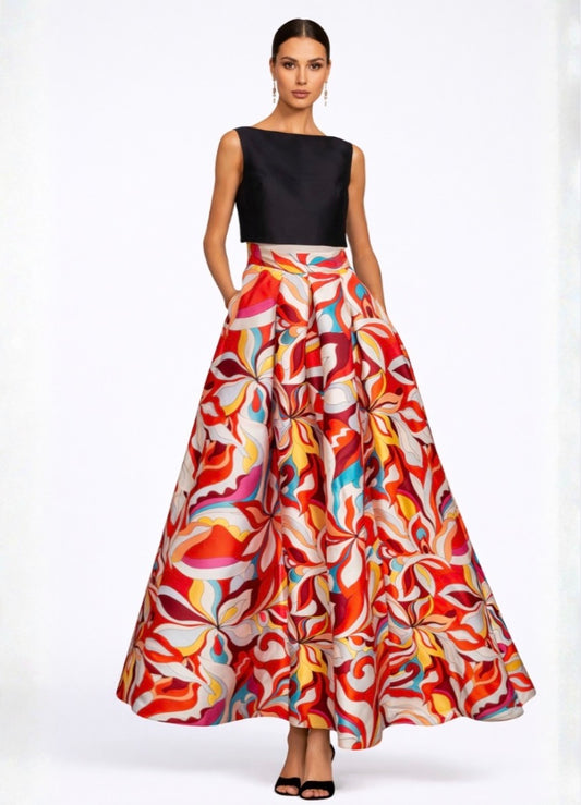 Woman wearing a black top and colorful patterned skirt on a white background