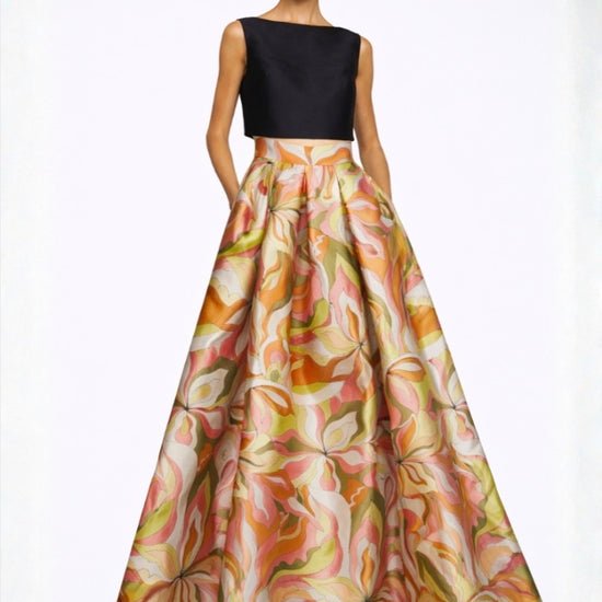 Woman wearing a black top and floral skirt on a white background