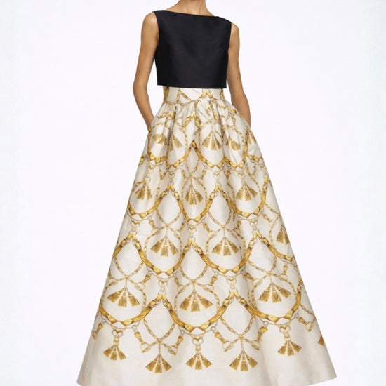 Woman wearing a black top and gold-patterned white skirt on a white background