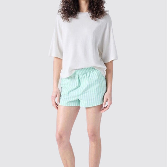 Woman wearing a white oversized shirt and light green shorts on a white background