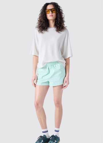 Woman wearing a white oversized shirt and light green shorts on a white background