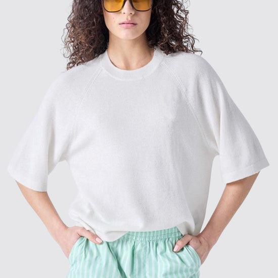 Person wearing a white oversized t-shirt and light green striped shorts on a plain background