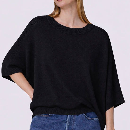 Woman wearing a black oversized cashmere sweater and blue jeans on a white background