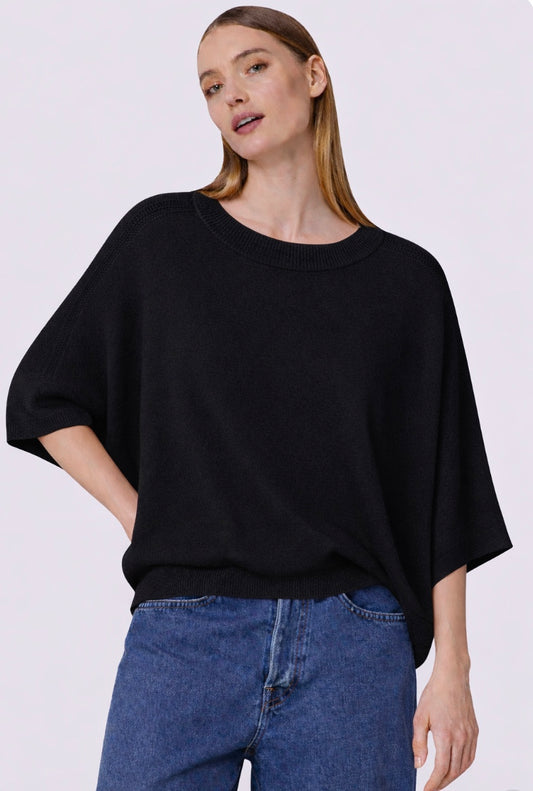 Woman wearing a black oversized cashmere sweater and blue jeans on a white background