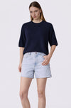 Woman wearing a navy blue top and light denim shorts on a white background