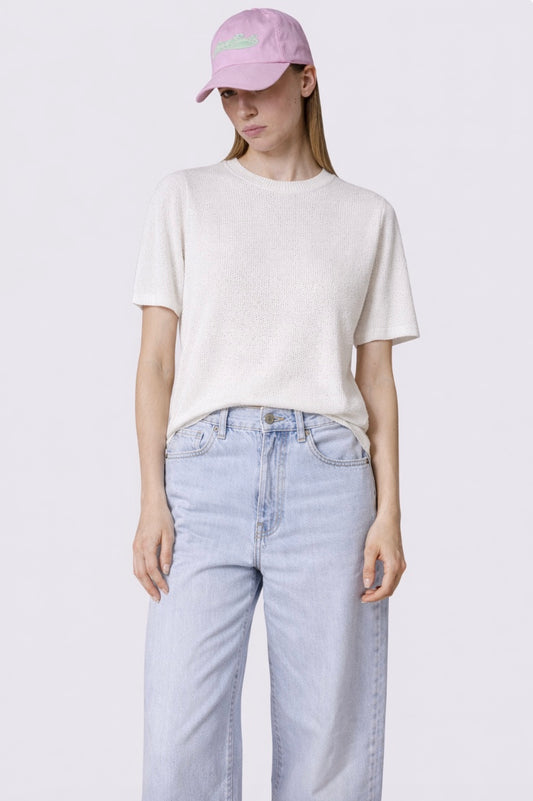 Person wearing a white t-shirt, light blue jeans, and a pink cap on a plain background