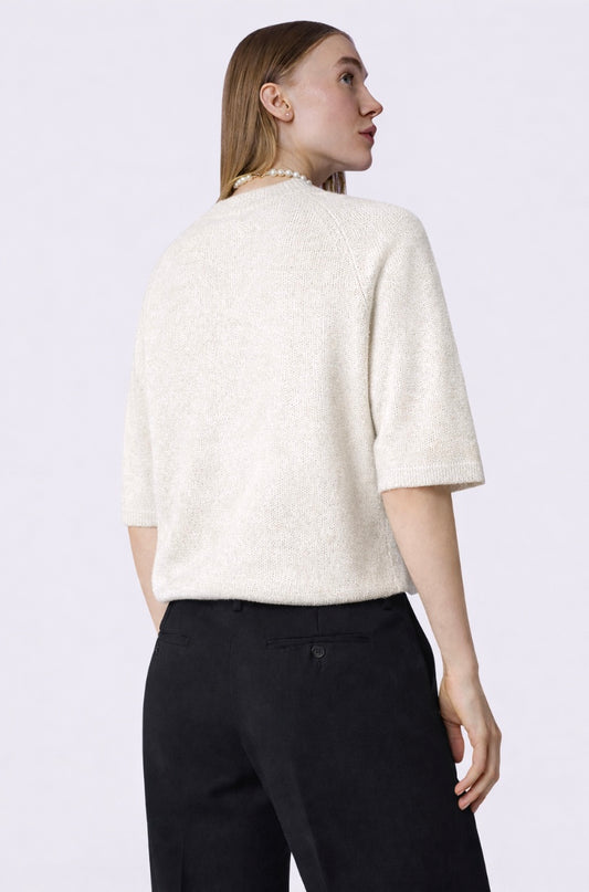 Woman wearing a white textured top and black pants on a light purple background