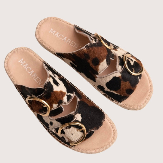 Cow print sandal with gold buckles and a woven sole 