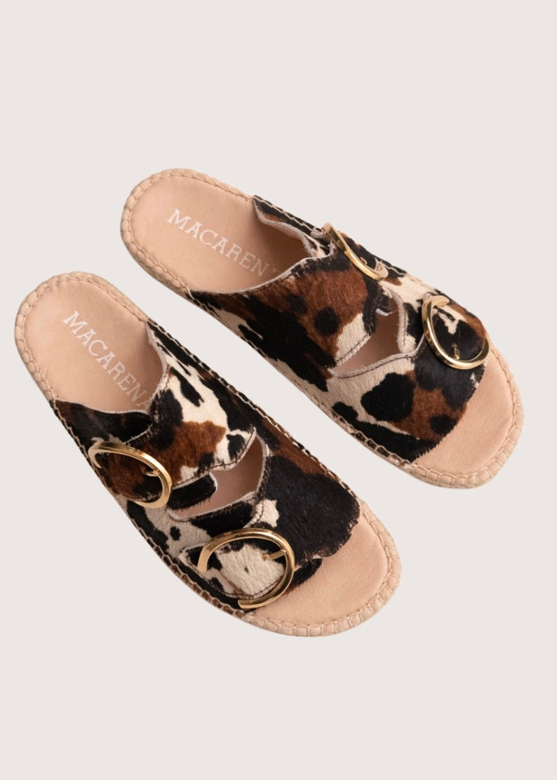 Cow print sandal with gold buckles and a woven sole 